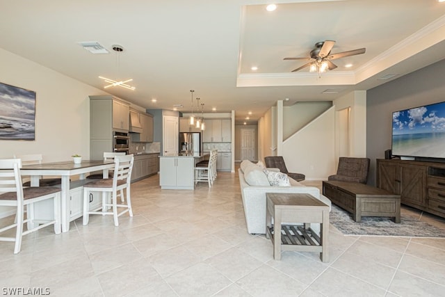 tiled living room with a tray ceiling, ornamental molding, and ceiling fan