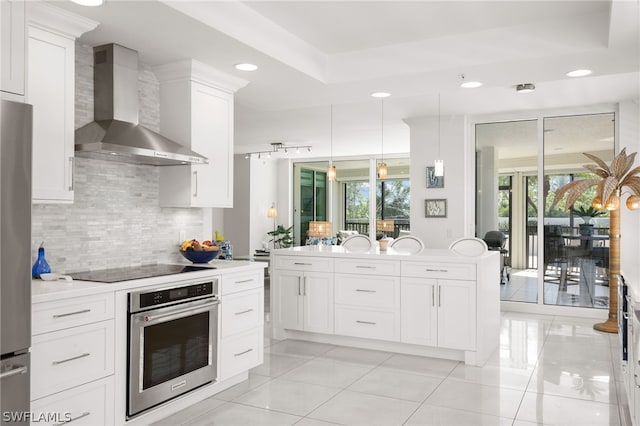 kitchen with stainless steel appliances, backsplash, pendant lighting, white cabinets, and wall chimney exhaust hood