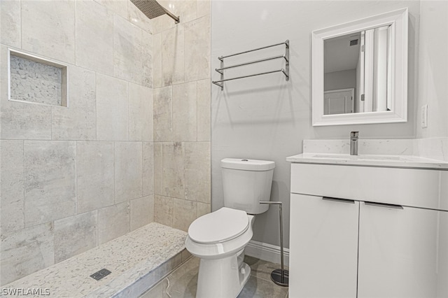 bathroom featuring toilet, tile flooring, large vanity, and a tile shower