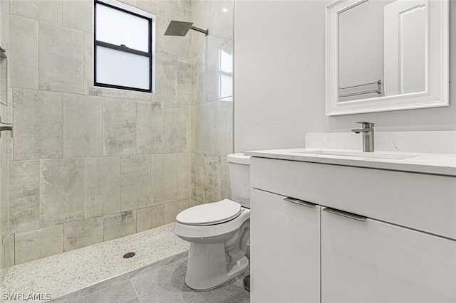 bathroom with vanity, a tile shower, tile floors, and toilet