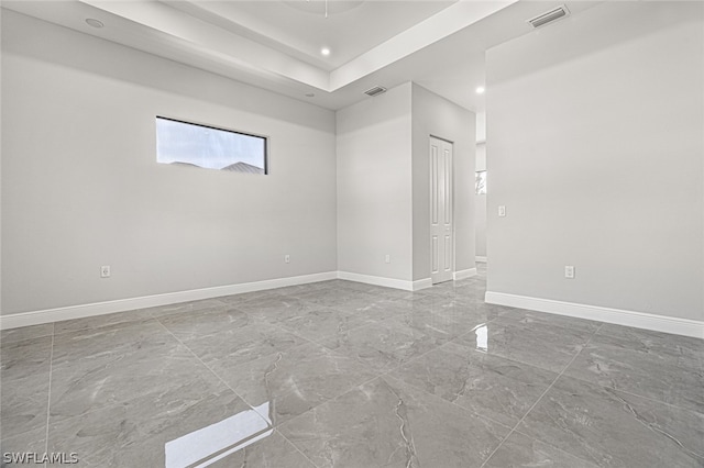 tiled spare room featuring a tray ceiling