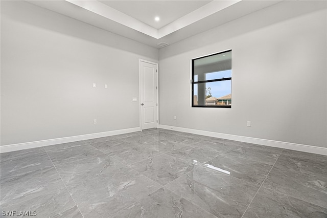 empty room with light tile floors and a tray ceiling