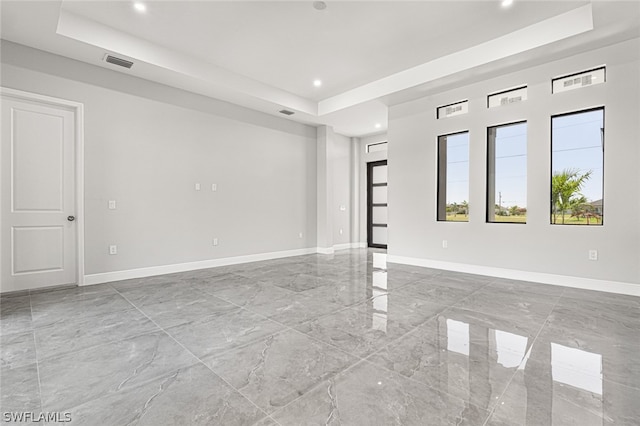 spare room with a raised ceiling and light tile floors