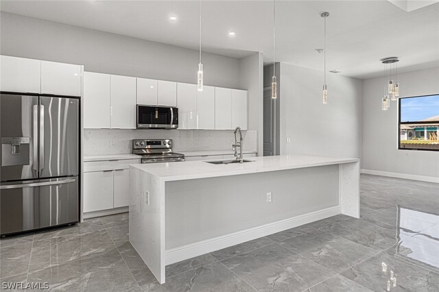 kitchen featuring white cabinets, backsplash, decorative light fixtures, and appliances with stainless steel finishes