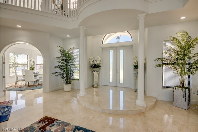 tiled foyer entrance featuring french doors, decorative columns, and a high ceiling