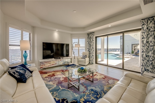 living room with light tile flooring and a raised ceiling