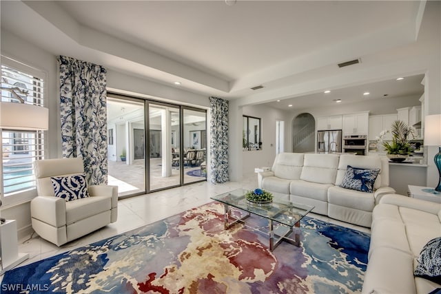 tiled living room with a healthy amount of sunlight and a tray ceiling