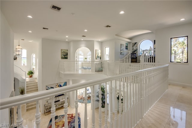 hall with a notable chandelier and light tile flooring