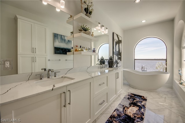 bathroom with tile floors, double sink, vanity with extensive cabinet space, and a washtub