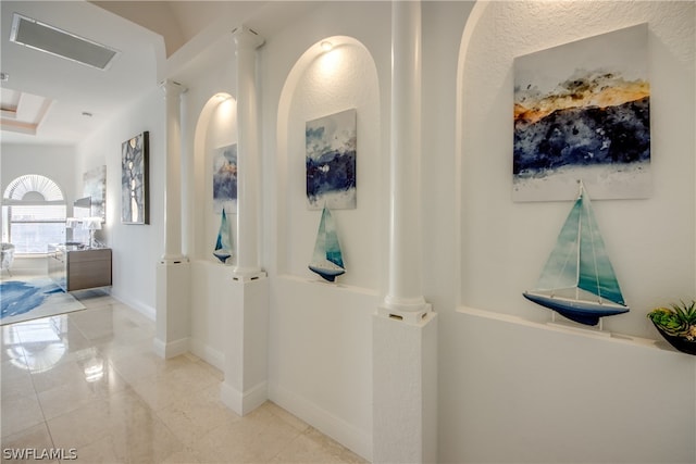 corridor featuring ornate columns and light tile flooring