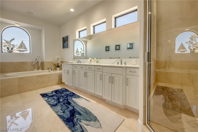 bathroom with vanity with extensive cabinet space, separate shower and tub, tile floors, and dual sinks