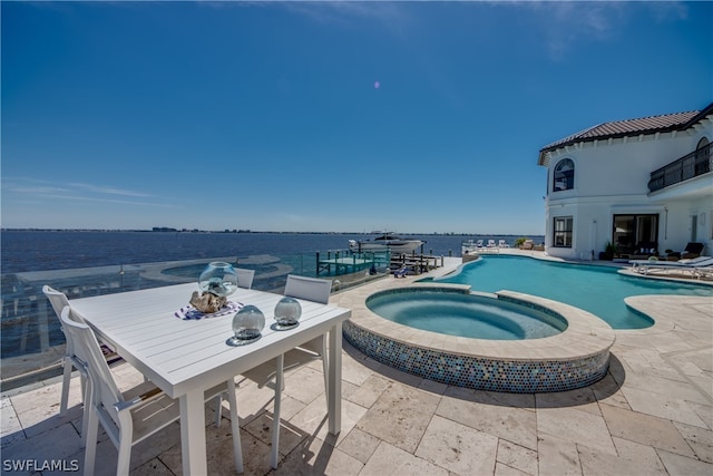 view of pool featuring a water view, a patio area, and an in ground hot tub