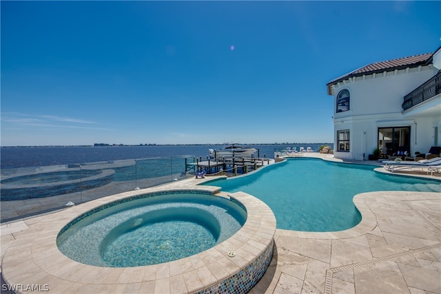 view of swimming pool featuring a water view, a patio area, and an in ground hot tub