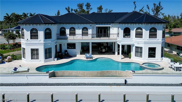 back of property featuring a balcony, a fenced in pool, and a patio