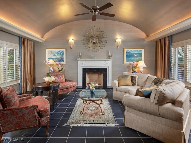 living room featuring lofted ceiling, ceiling fan, a premium fireplace, and a healthy amount of sunlight