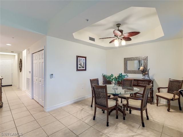 tiled dining room featuring a tray ceiling and ceiling fan