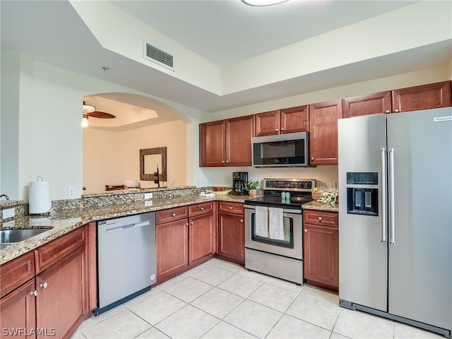 kitchen with light stone countertops, stainless steel appliances, ceiling fan, sink, and light tile patterned floors