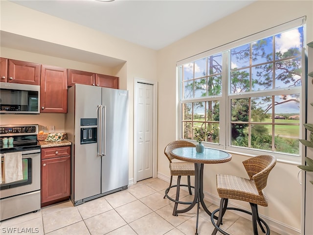 kitchen featuring light tile patterned flooring, light stone counters, and stainless steel appliances