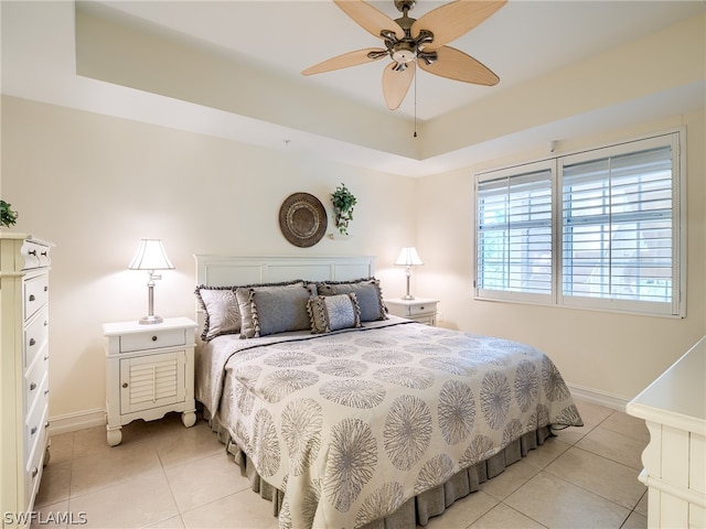 bedroom featuring a raised ceiling, ceiling fan, and light tile patterned flooring