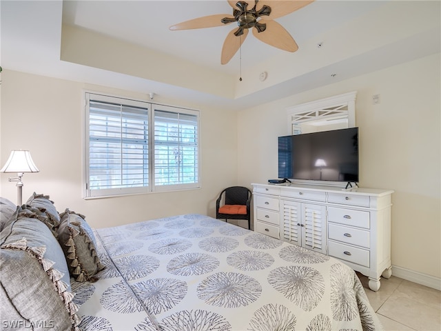 tiled bedroom featuring ceiling fan and a raised ceiling