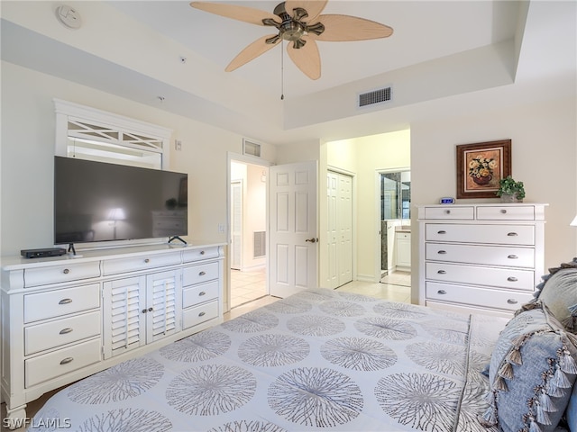 bedroom featuring ensuite bathroom, a raised ceiling, ceiling fan, a closet, and light tile patterned flooring