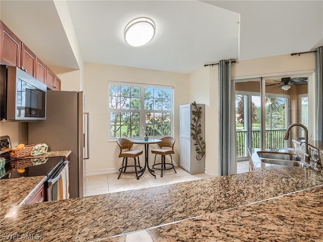 kitchen featuring stone counters, sink, light tile patterned floors, and stainless steel appliances