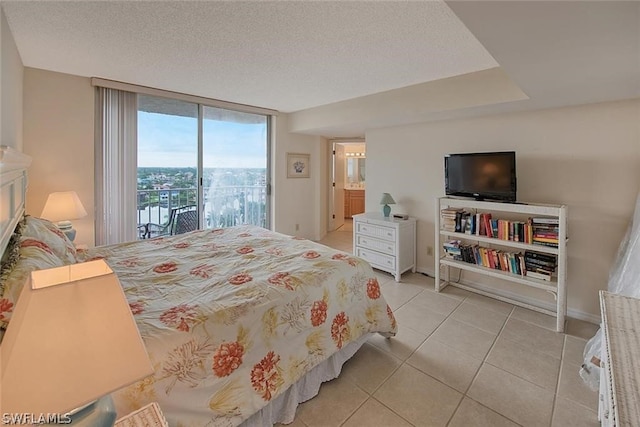 bedroom with a textured ceiling, light tile patterned flooring, access to outside, floor to ceiling windows, and ensuite bath