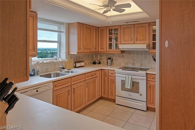 kitchen with a tray ceiling, white appliances, a sink, and light countertops