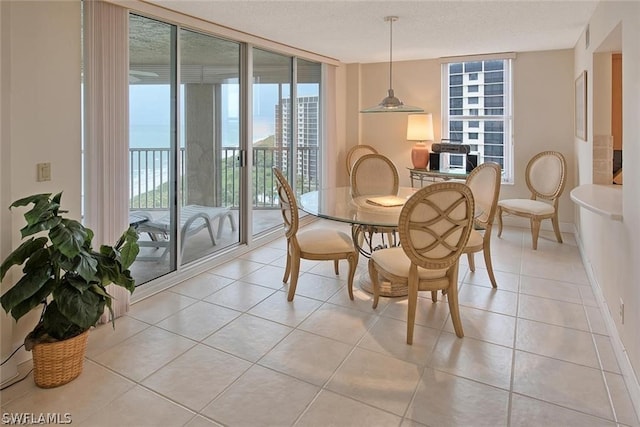 dining area featuring baseboards, a wall of windows, a textured ceiling, and light tile patterned flooring