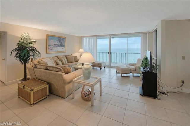 living area featuring expansive windows, light tile patterned flooring, a textured ceiling, and baseboards