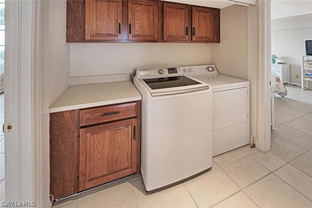 washroom with cabinets, washing machine and dryer, and light tile floors