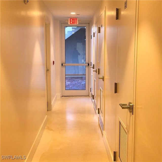 hall featuring visible vents, concrete floors, and baseboards