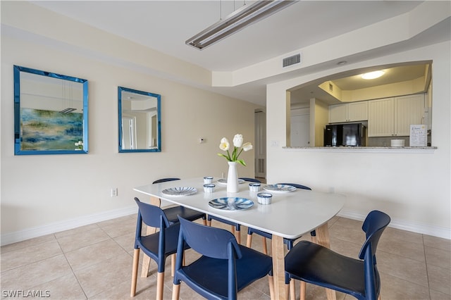 tiled dining space featuring a raised ceiling