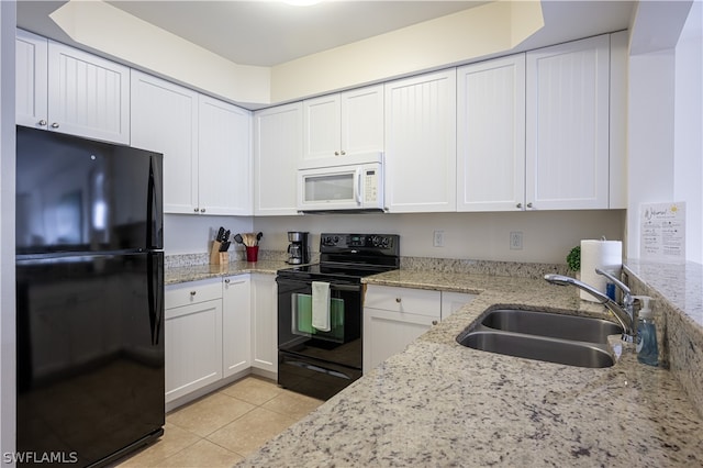 kitchen with white cabinets, light stone counters, black appliances, and sink