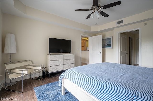 bedroom with a raised ceiling, dark hardwood / wood-style flooring, and ceiling fan