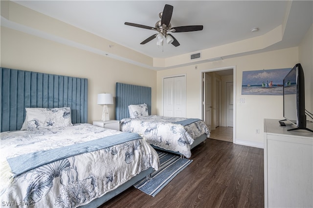 bedroom with a raised ceiling, a closet, ceiling fan, and dark hardwood / wood-style floors