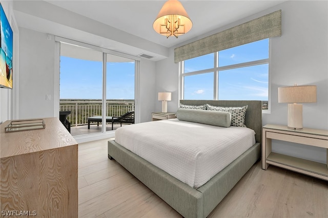 bedroom featuring a chandelier, access to exterior, light hardwood / wood-style floors, and multiple windows