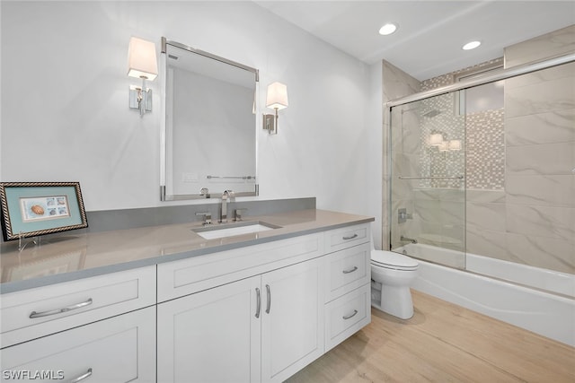 full bathroom featuring shower / bath combination with glass door, toilet, vanity, and hardwood / wood-style flooring