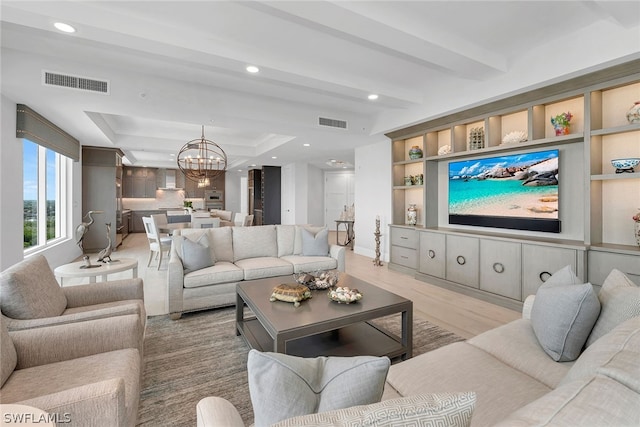 living room with a notable chandelier, a tray ceiling, and light hardwood / wood-style flooring