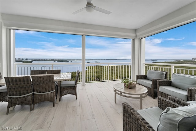 sunroom / solarium featuring ceiling fan and a water view