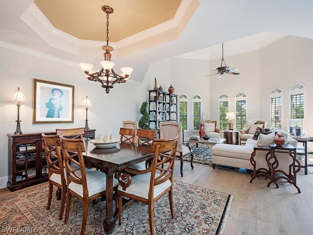 dining area featuring crown molding, a tray ceiling, and light wood-style floors