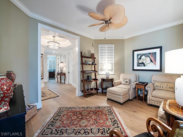 living area featuring a ceiling fan, crown molding, light wood-style flooring, and baseboards