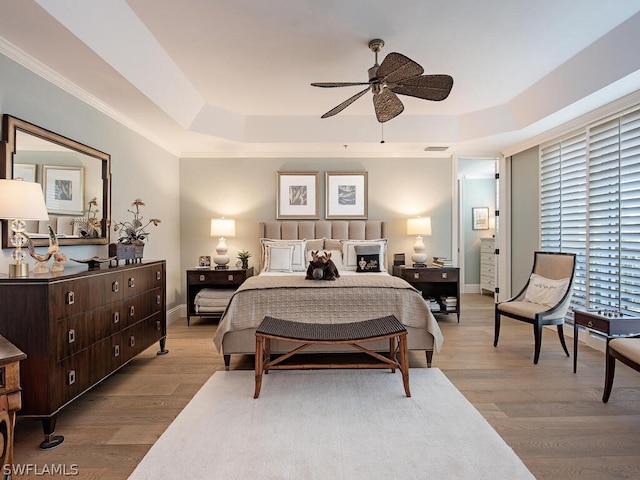 bedroom featuring wood finished floors, a fireplace, a raised ceiling, and baseboards