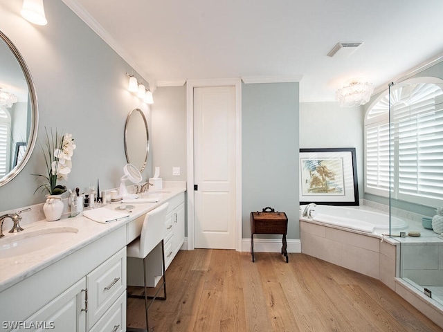 full bath featuring wood finished floors, a sink, visible vents, a bath, and double vanity