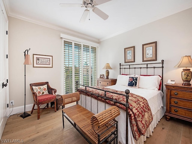 bedroom with crown molding, baseboards, and wood finished floors