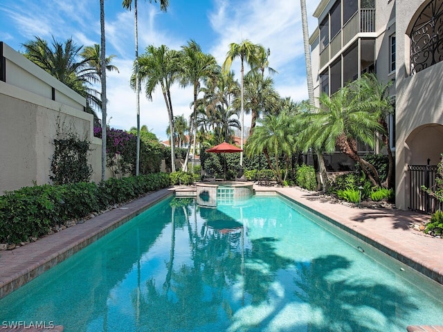 view of pool with a pool with connected hot tub and fence