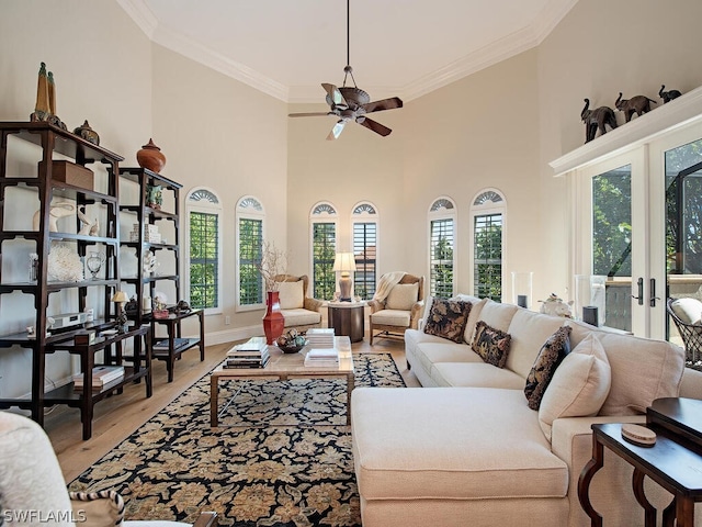 living area featuring french doors, crown molding, light wood-style flooring, ceiling fan, and baseboards