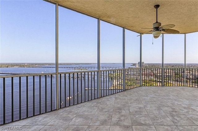 unfurnished sunroom featuring ceiling fan and a water view