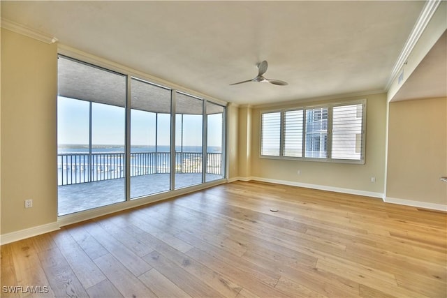 spare room with a water view, ceiling fan, light hardwood / wood-style floors, and a wealth of natural light