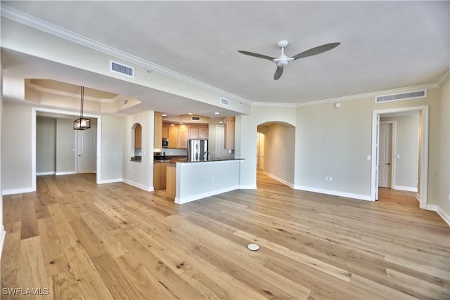 unfurnished living room featuring a tray ceiling, crown molding, light hardwood / wood-style flooring, and ceiling fan